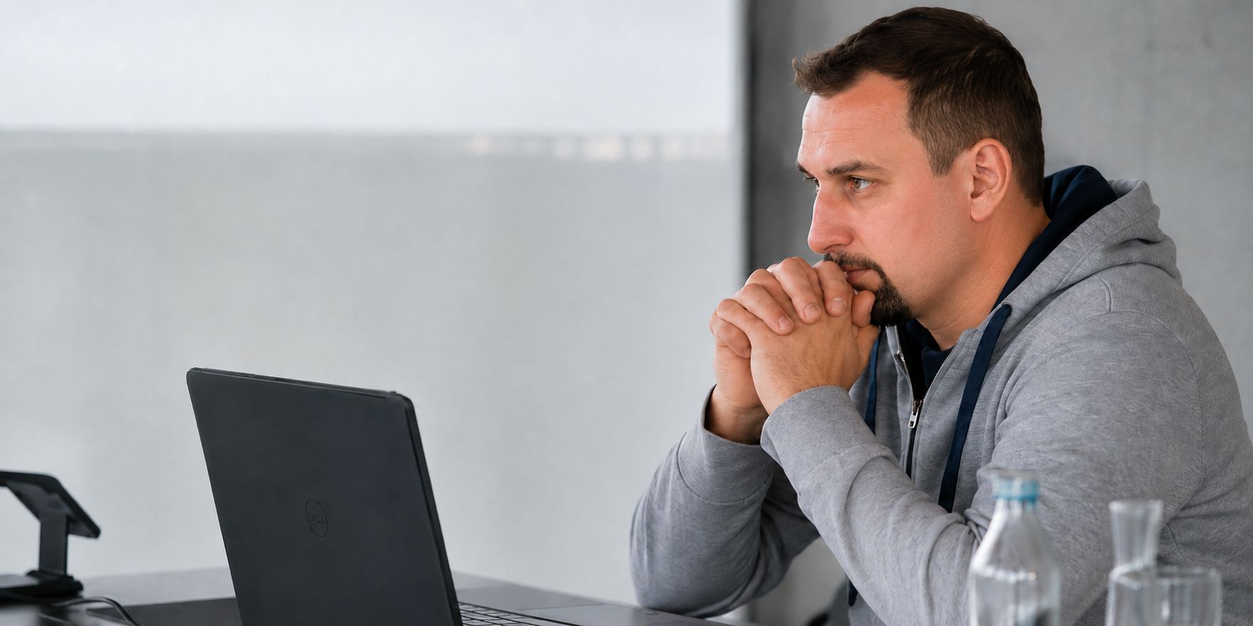Rafał Wesołowski sitzt konzentriert vor einem Laptop, die Hände vor dem Gesicht gefaltet.